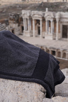 Dark gray towel on stone steps with ancient ruins in the background