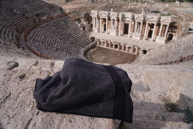 Dark gray towel on a stone surface with an ancient amphitheater in the background
