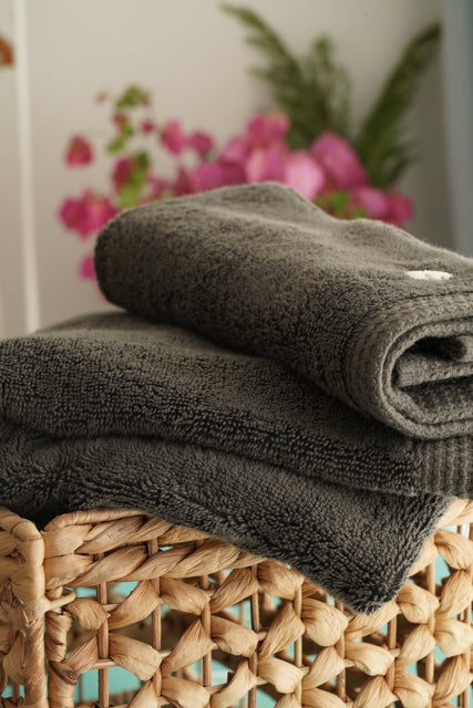 Minoa USA Canada Jasper organic Aegean cotton luxury bath towel set in a basket with a flowers background, highlighting soft plush texture and sustainable luxury