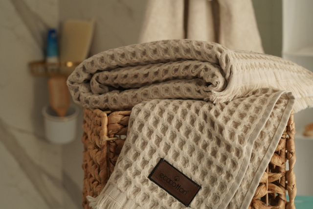 Close-up of Minoa USA Canada Seren organic cotton waffle luxury bath towels in a shower room, showing their plush texture, elegance, and sustainable luxury