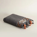 Folded textured towel with geometric pattern and tassels on a light background