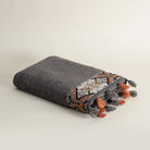 Folded textured towel with geometric pattern and tassels on a light background