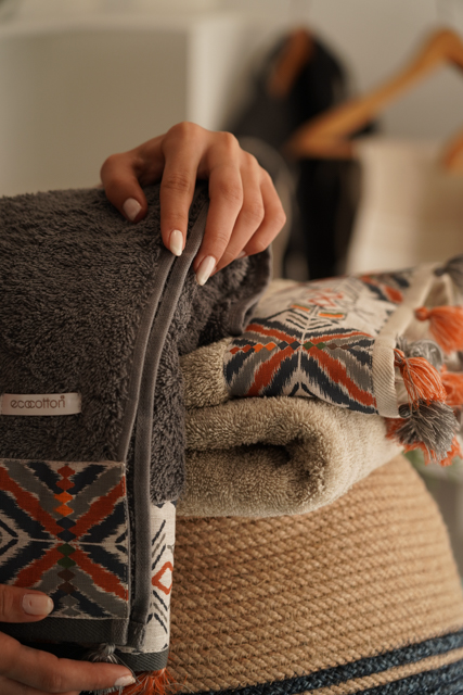 Stack of patterned towels with a hand holding one, blurred background