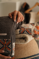 Stack of patterned towels with a hand holding one, blurred background