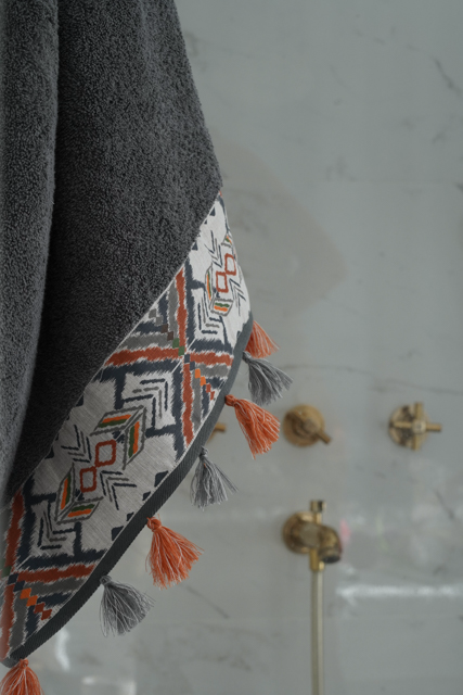 Towel with geometric patterns and tassels hanging on a wall.