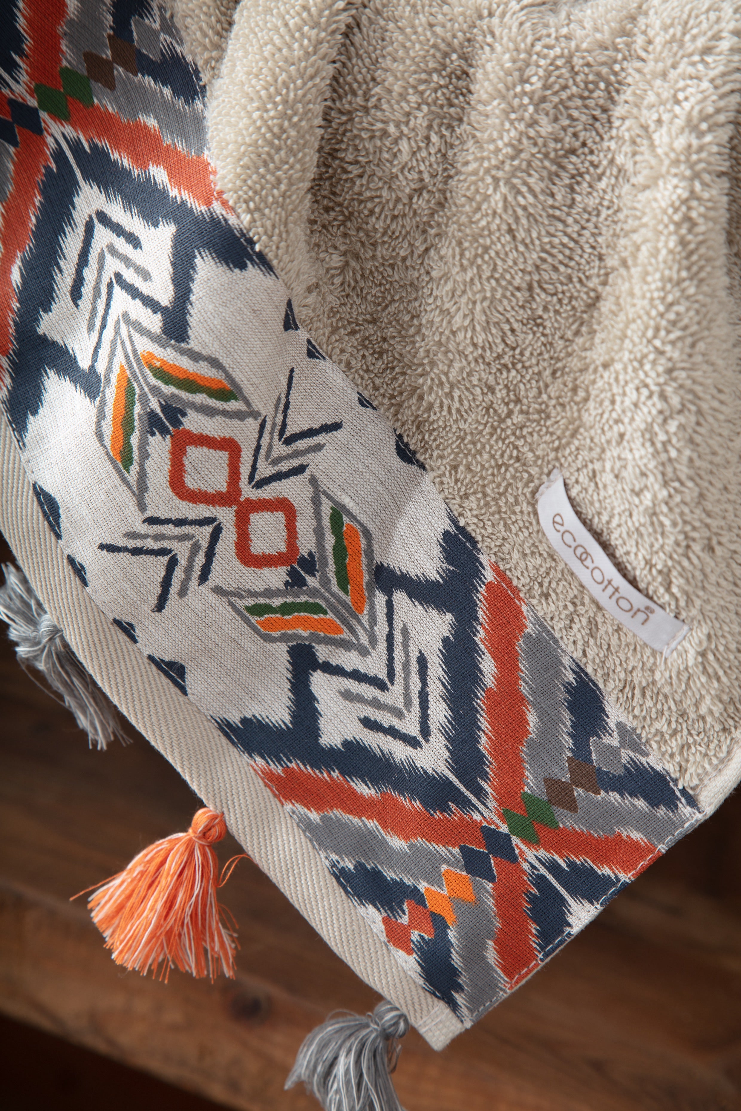 Towel with geometric pattern and tassels on a wooden surface