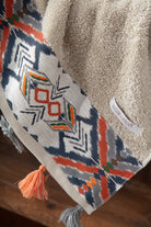 Towel with geometric pattern and tassels on a wooden surface