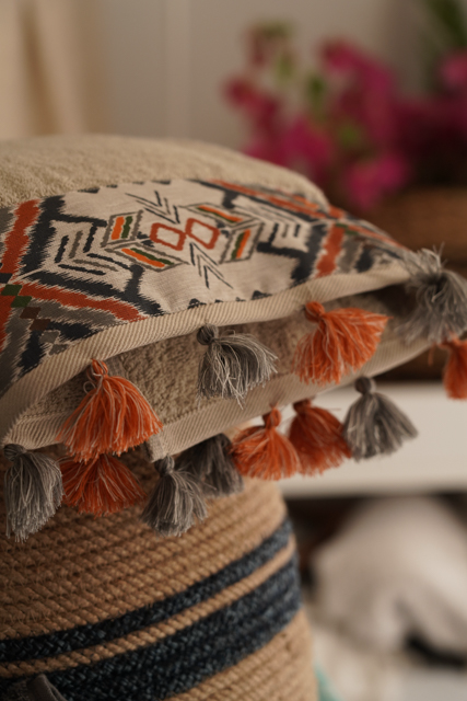 Stack of decorative towels with geometric patterns and tassels on a blurred background