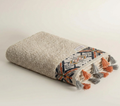 Folded towel with geometric pattern and tassels on a light background