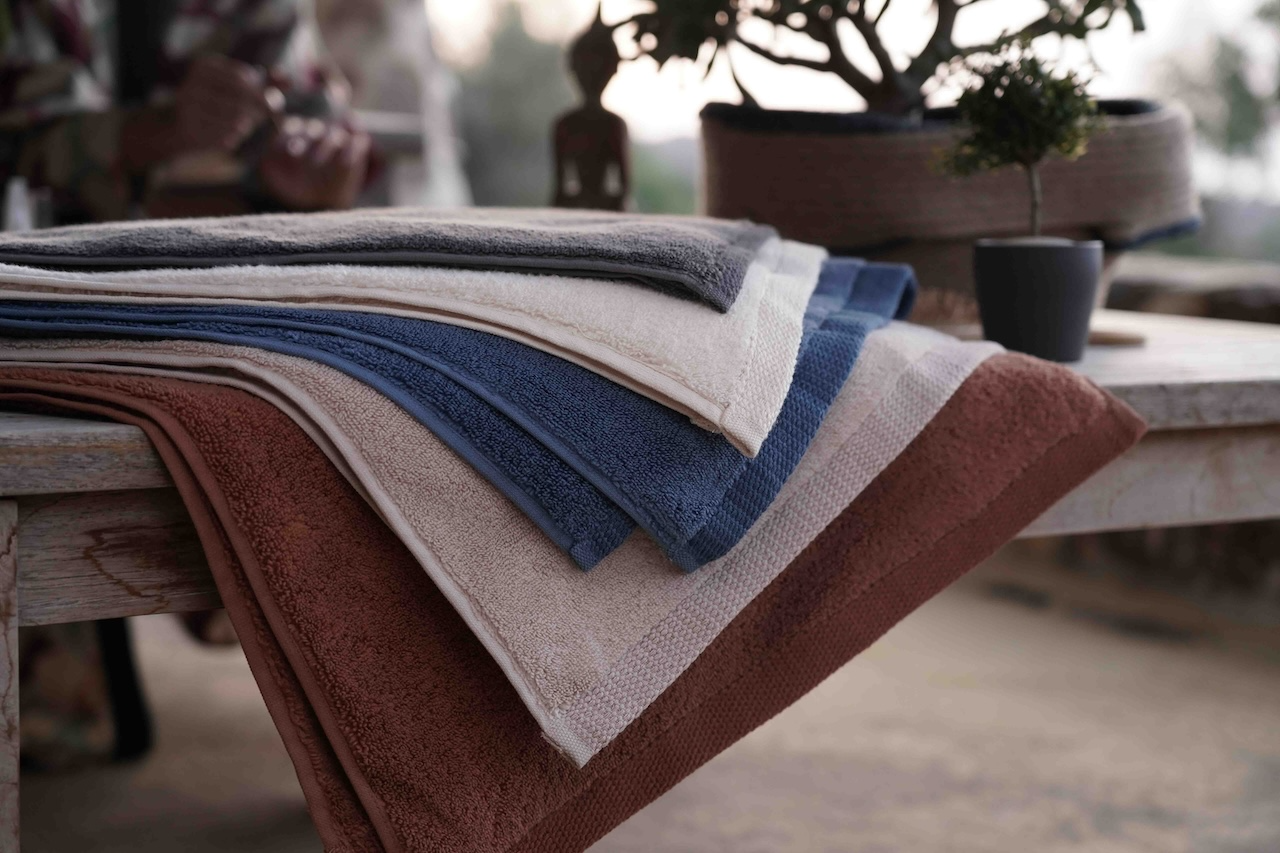 Stack of folded towels in various colors on a wooden surface with a blurred background
