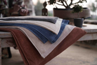 Stack of folded towels in various colors on a wooden surface with a blurred background