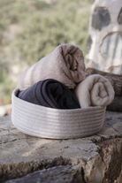 Folded towels in a woven basket on stone steps with a natural background