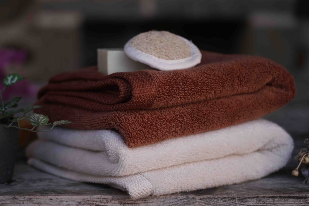 Stack of folded brown and white towels on a wooden surface with a blurred background