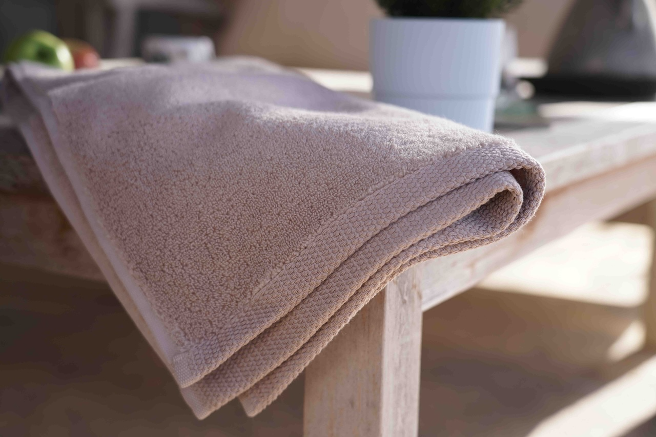 Folded beige towel on a wooden table with a blurred background