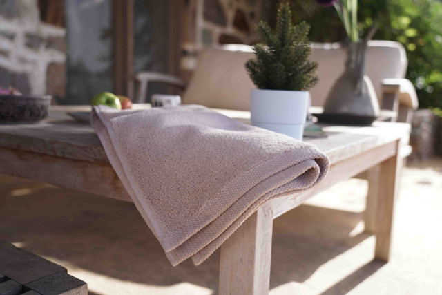 Beige towel draped over a wooden table with a blurred outdoor background