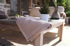Beige towel draped over a wooden table with a blurred outdoor background