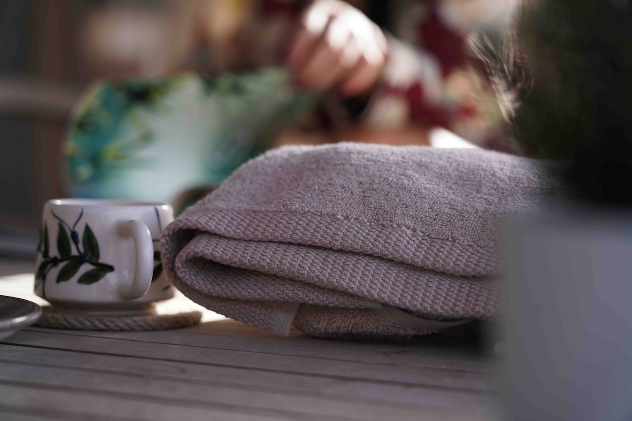Grey towel and mug on a wooden surface with blurred background