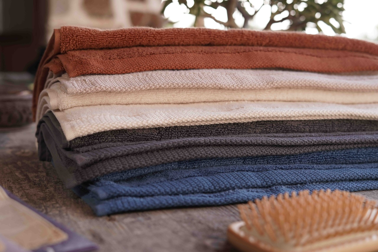Stack of folded towels in various colors on a surface with a blurred background