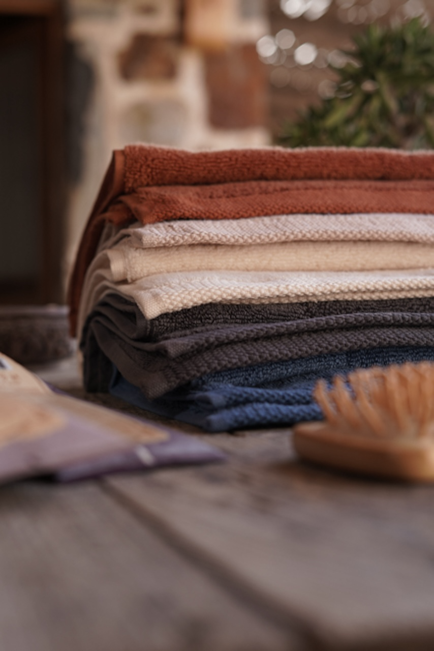 Stack of folded towel in various colors on a wooden surface.