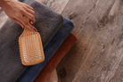Hand holding a wooden brush over folded towels on a wooden surface