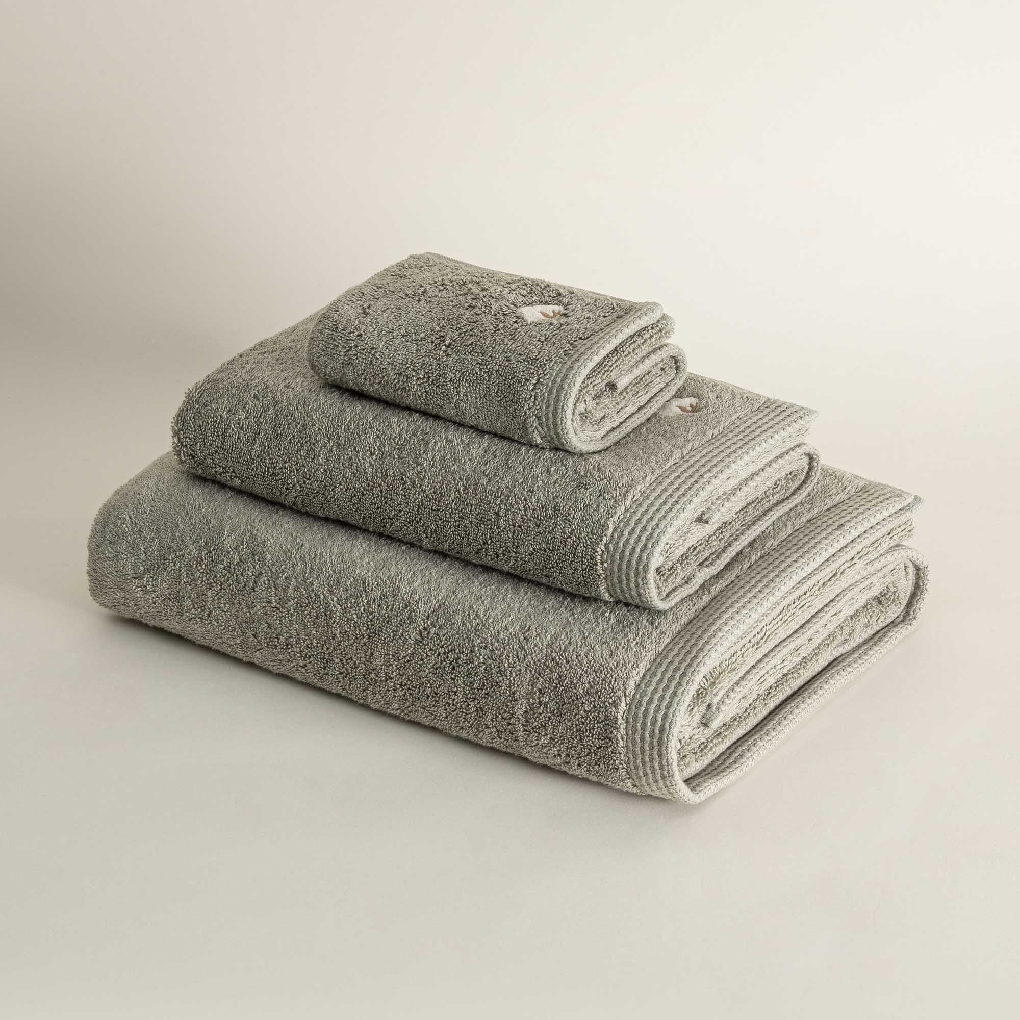 Side view of three folded Jasper 600-gram organic Aegean cotton luxury bath, hand, and washcloth towels in Mossy Muse, highlighting soft plush texture, earthy tone, and luxurious fabric
