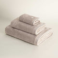 Set of three folded towels in beige on a light gray background