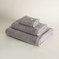 Set of three folded gray towels on a light beige background