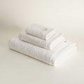 Set of white towels stacked on a light beige background