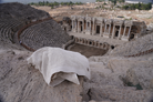 Towel draped over a stone in an ancient amphitheater with ruins in the background