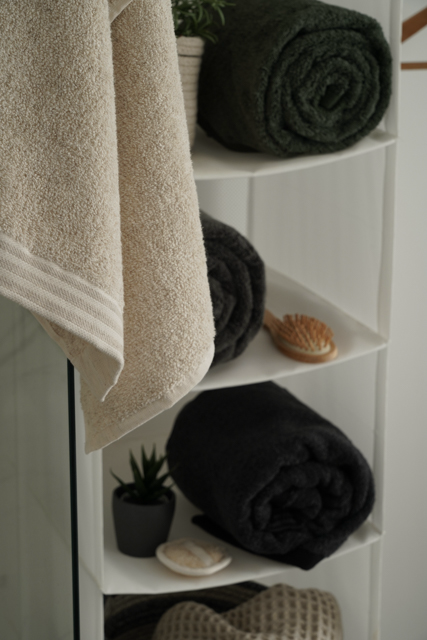 Towels and rolled-up towels on a white shelf with decorative items.