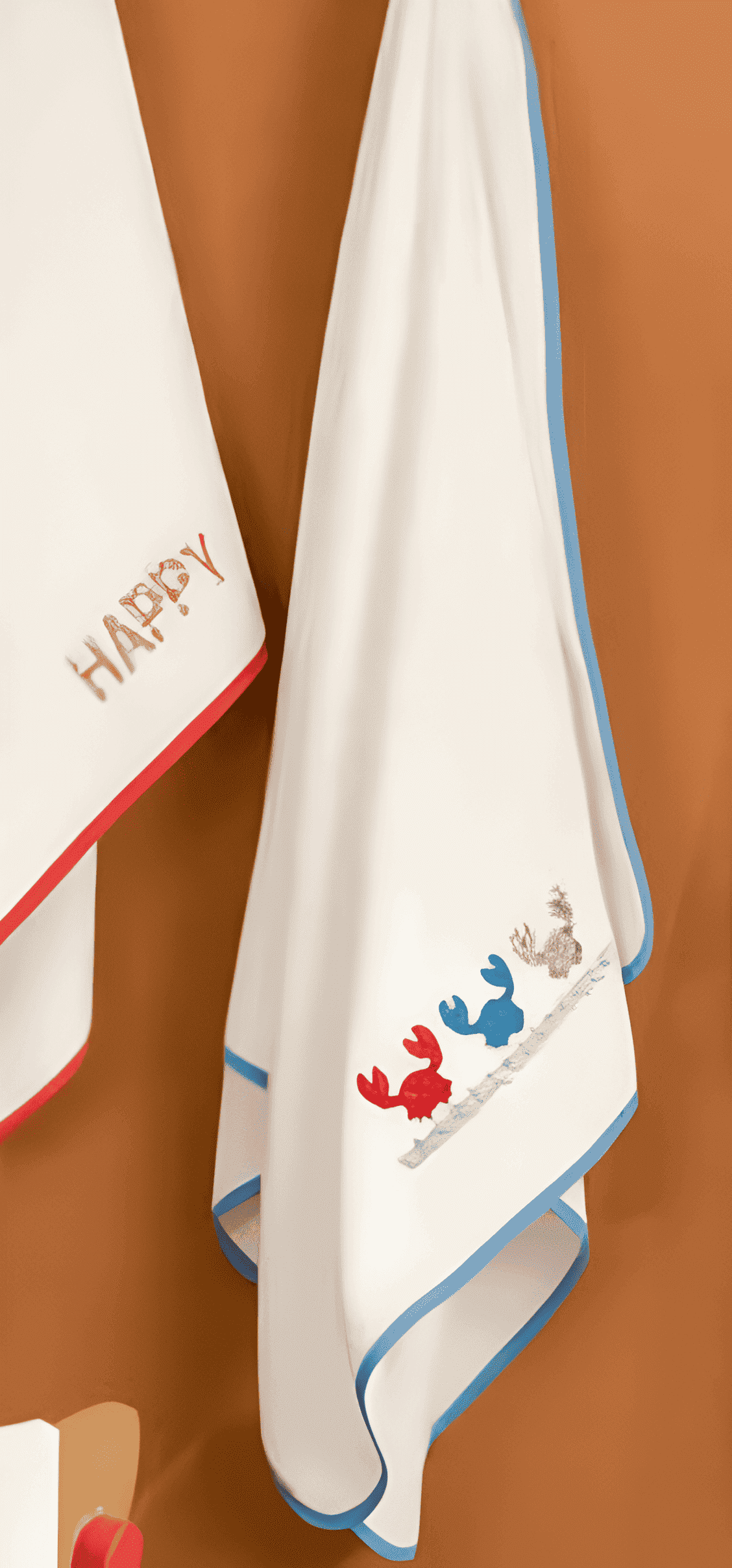 Two baby towels with embroidered designs on a brown background