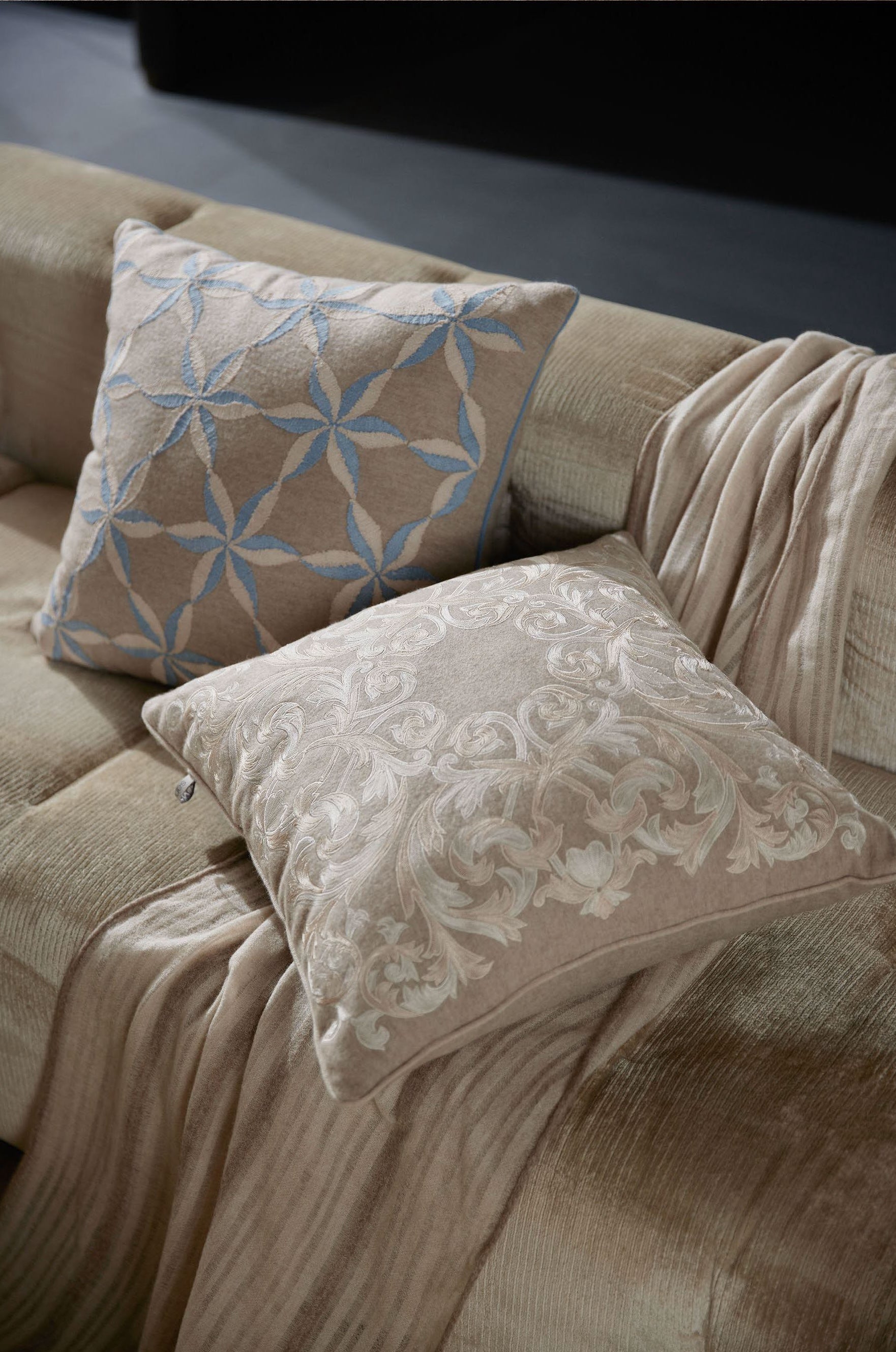Two luxury cushions with different patterns placed on a golden sofa, highlighting rich textures and elegant design.