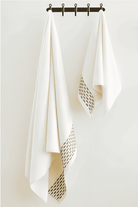Two Calm 550-GSM Cotton Towels in ivory and green, organic cotton towels hanging on a towel hanger, showcasing their soft texture and soothing color combination.
