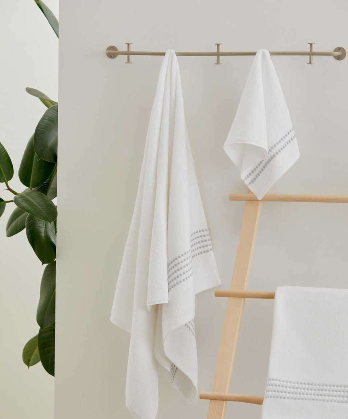 Two Classy 460-GSM Cotton/Viscose Towels in white, organic cotton towels hanging on a towel hanger, showcasing their soft texture and luxurious, fresh look.