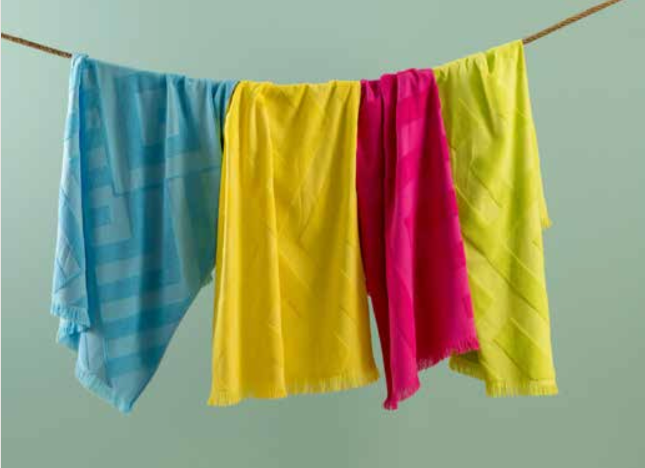 Four pieces of PESHTEMAL Maris Towel hanging on a clothes line (blue, yellow, pink, green from left to right)
