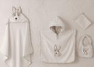 Baby blanket, hooded towel, and bib with dog design on a textured beige background