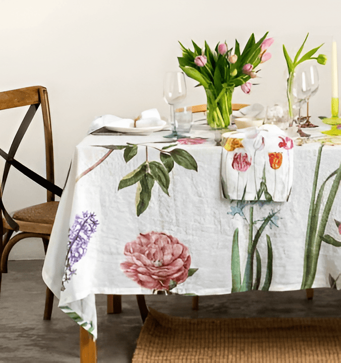 Table setting with floral tablecloth and tulips on a white wall background
