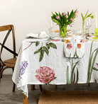 Table setting with floral tablecloth and tulips on a white wall background