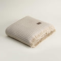 Beige textured towel with frayed edges on a light beige background