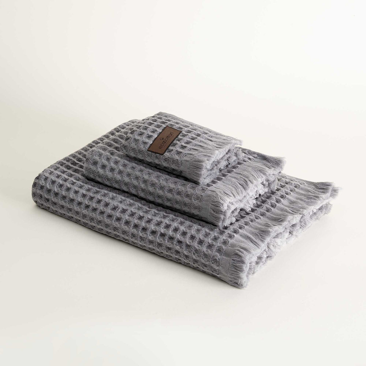 Three-piece Silver Delight Seren Organic Cotton Waffle Bath Set, including bath towel, hand towel, and washcloth, gently arranged to highlight its soft texture and natural, eco-friendly design