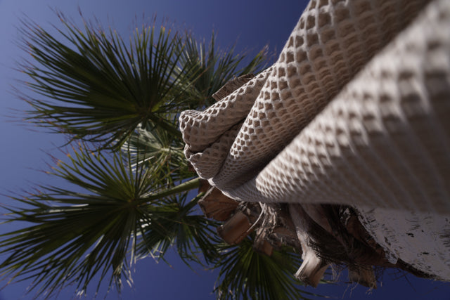 Minoa Seren organic cotton waffle luxury bath towels hanging from a tree, showcasing sustainable luxury with eco-friendly design and soft plush texture