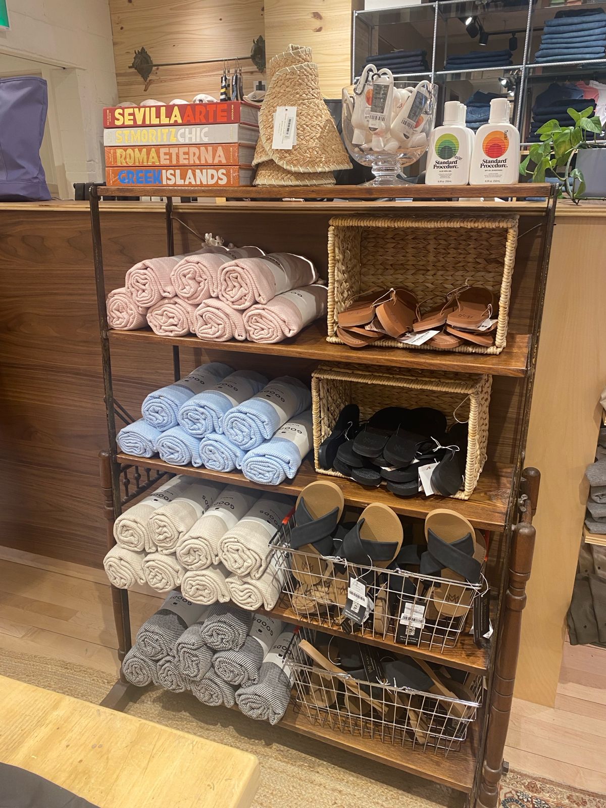 Wooden shelf with folded towels and bags in a store setting