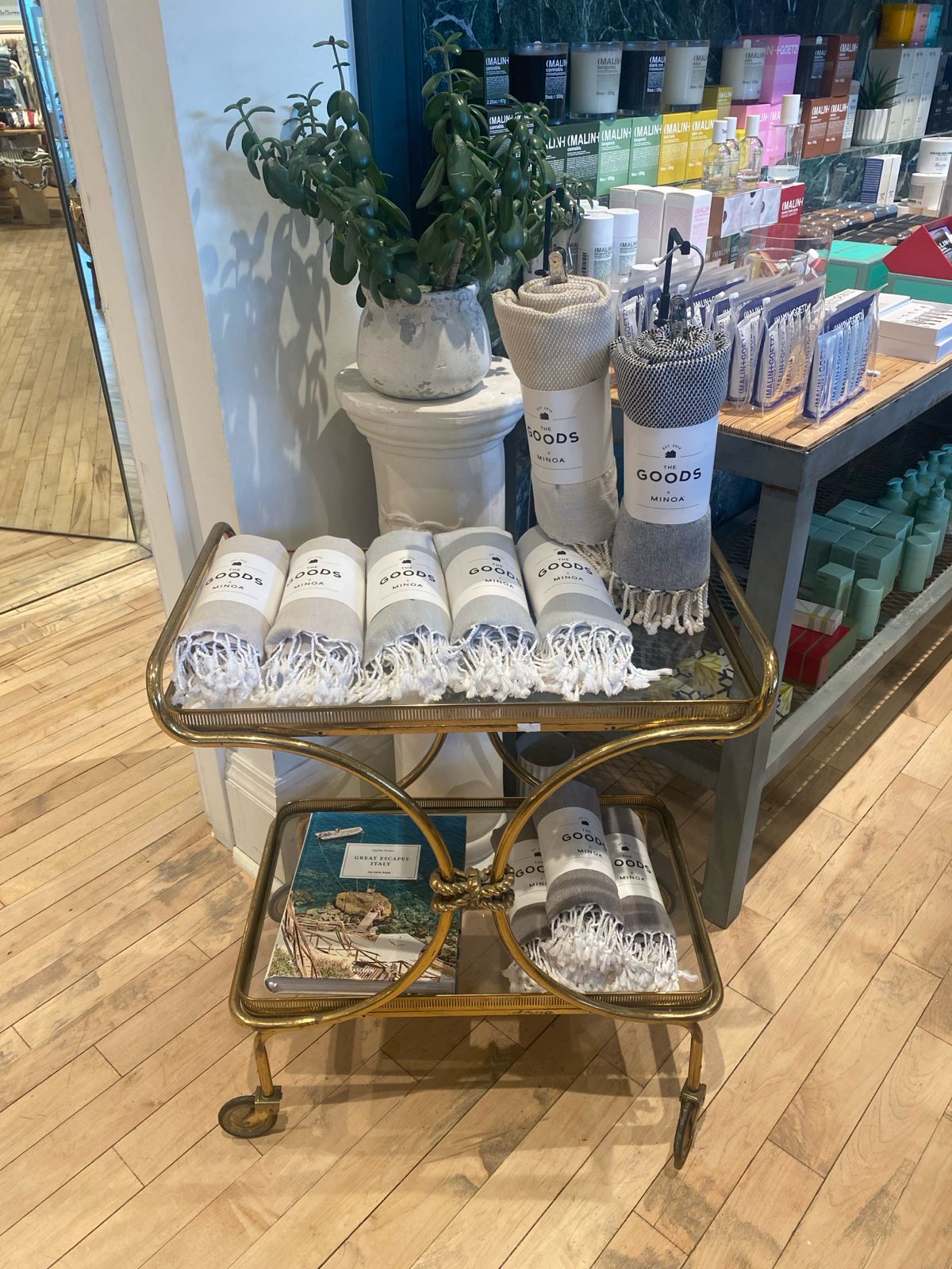 Decorative cart with rolled-up towels labeled 'goods' in a store setting.