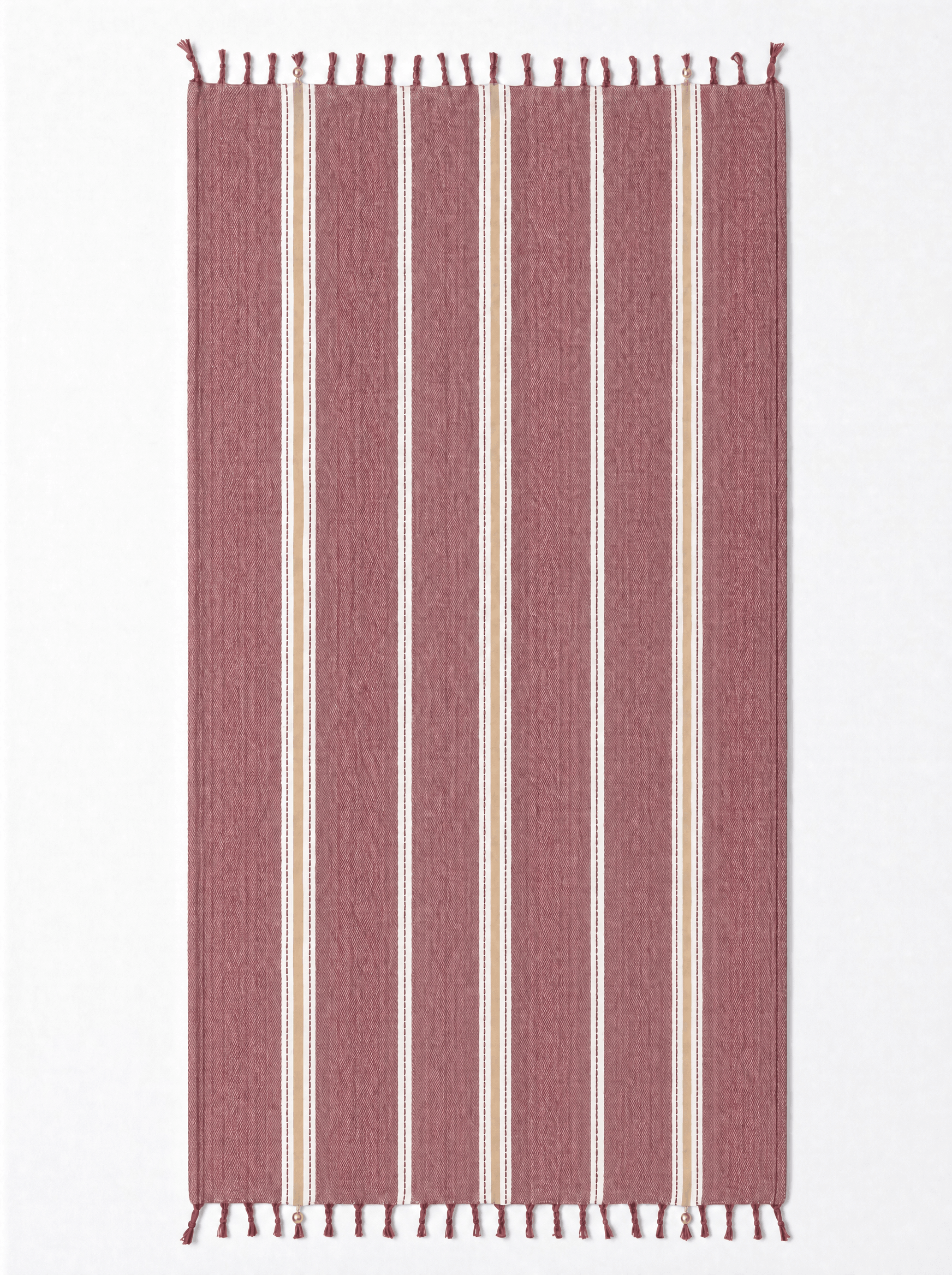 A rectangular woven towel with vertical stripes in dusty rose, cream, and white, finished with small fringe tassels at the top and bottom, shown flat against a plain white background.