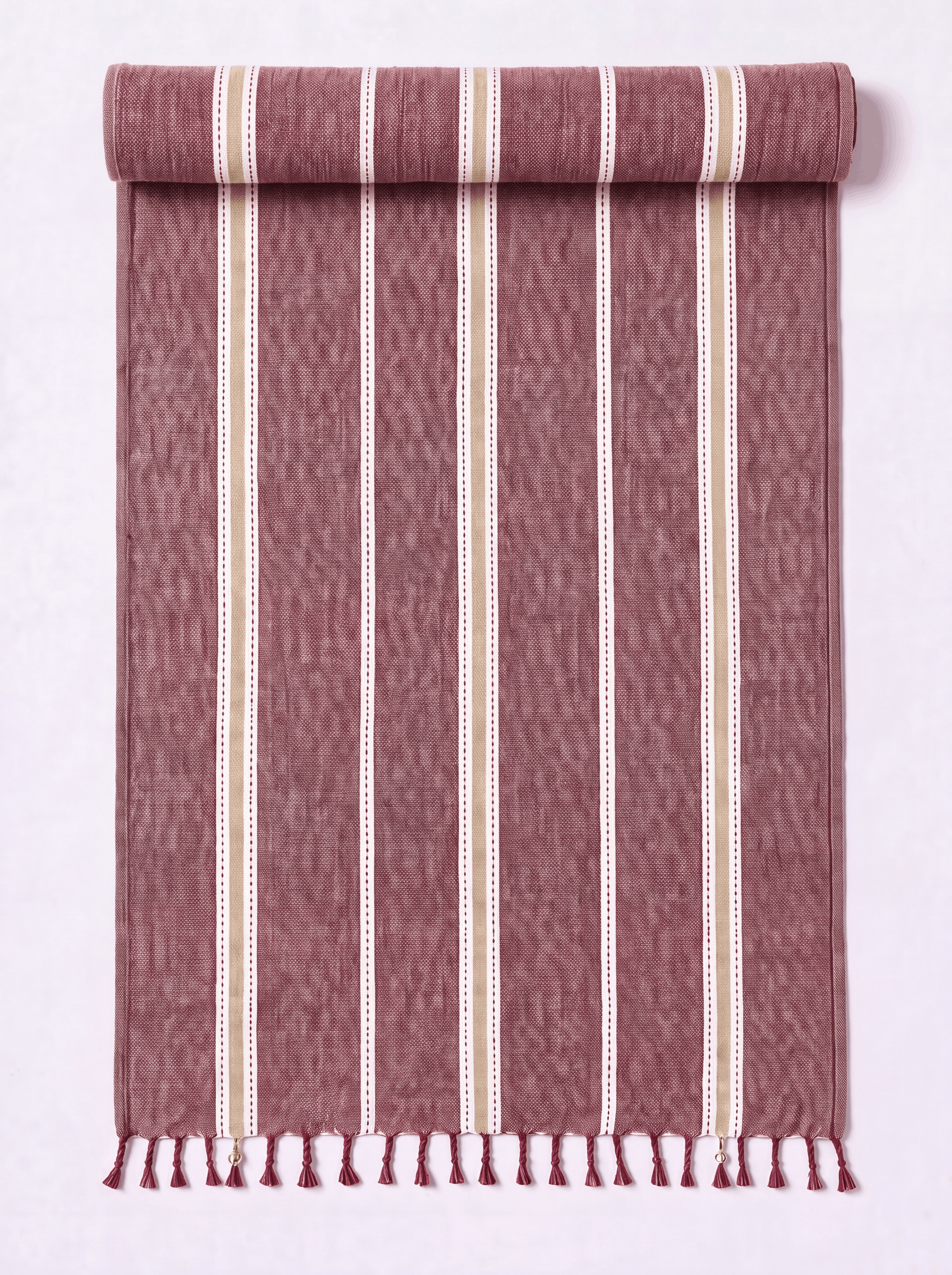 A rolled and unrolled woven towel featuring vertical stripes in dusty rose, cream, and white. The fabric has a textured ikat-like weave and finished with a fringed tassel edge at the bottom, displayed against a clean white background.