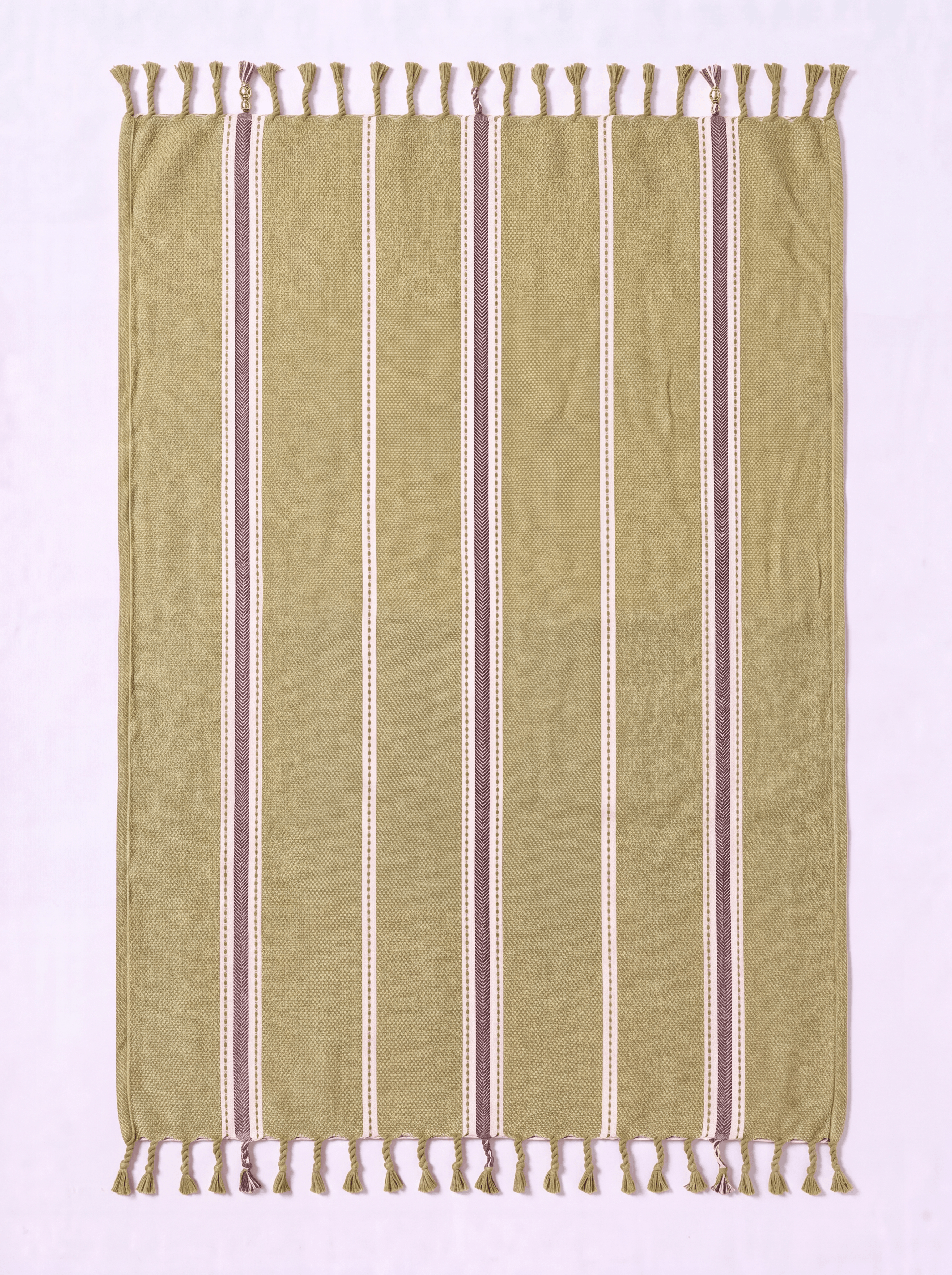 A rectangular woven towel with fringe on both short ends, shown flat against a pale pink background. The fabric is predominantly olive green with vertical stripes in cream, white, and muted mauve-brown.