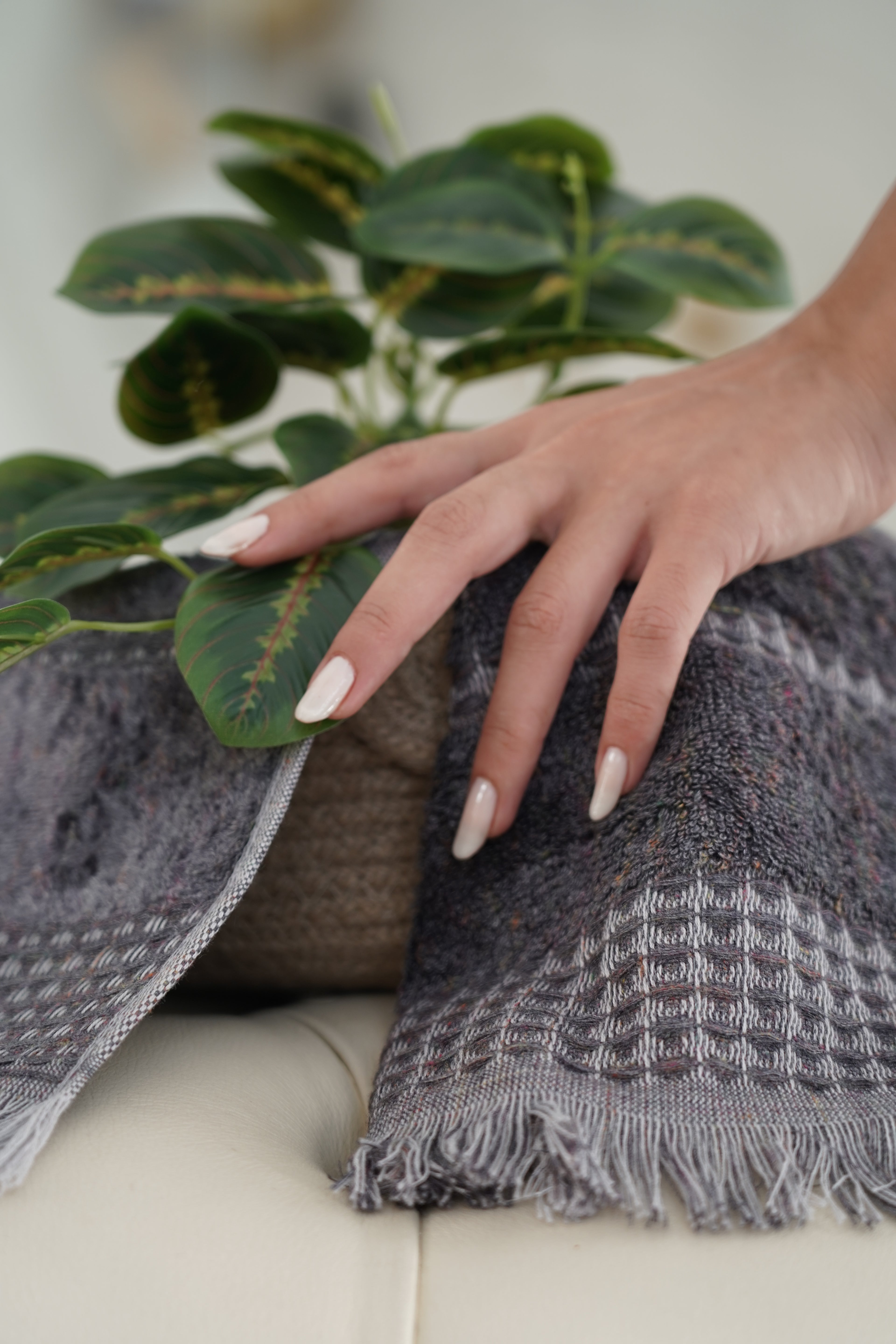  Zeus Organic Cotton Bath, Hand & Washcloth Set in Cozy Cobalt, with a woman’s hand gently holding the towels, accompanied by a plant, highlighting the soft texture, vibrant colour, and natural aesthetic