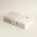 Two folded towels with a brand logo on a beige background