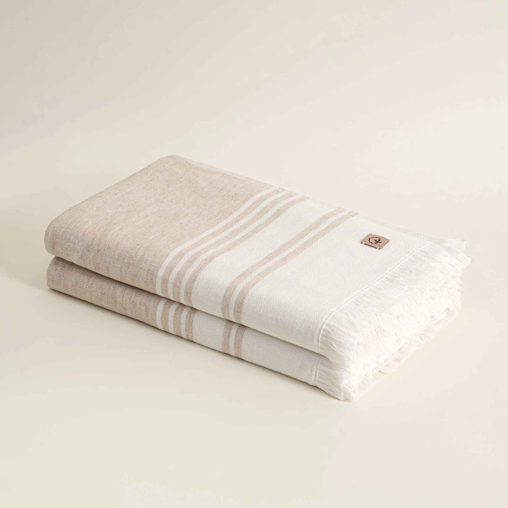 Two folded towels with a brand logo on a beige background