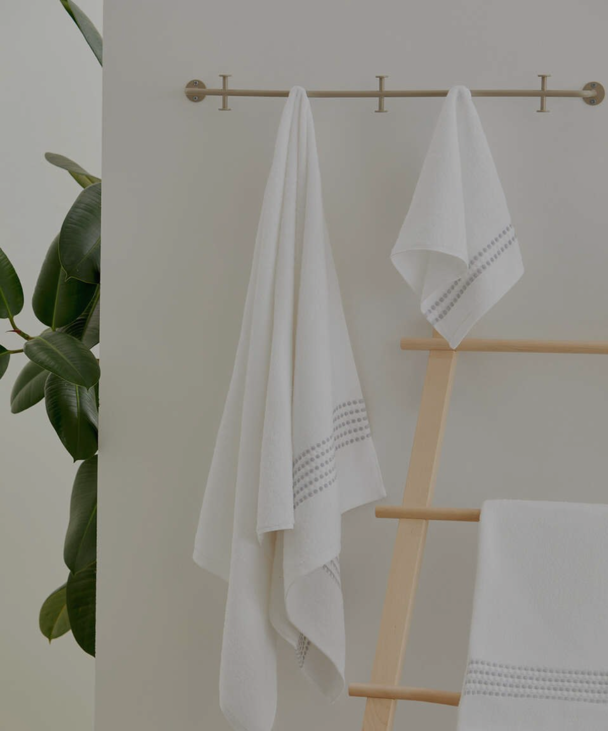 Two Classy 460-GSM Cotton/Viscose Towels in white, organic cotton towels hanging on a towel hanger, showcasing their soft texture and luxurious, fresh look.